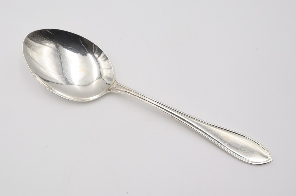 A comprehensive silver cutlery set containing dinner knives, forks, soup spoons, and dessert spoons laid out flat on a light grey background. View VI