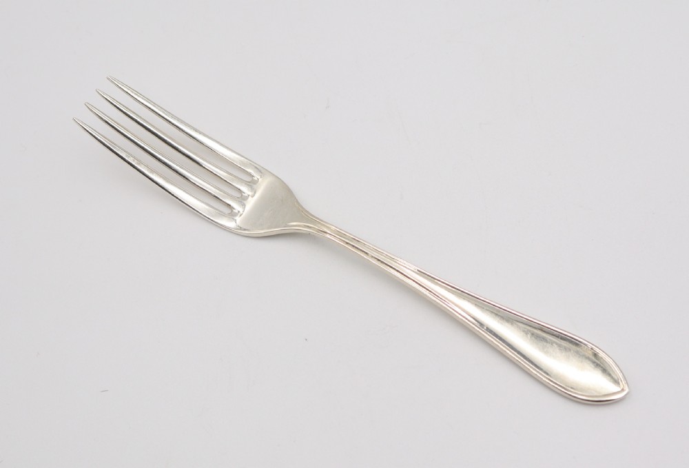 A comprehensive silver cutlery set containing dinner knives, forks, soup spoons, and dessert spoons laid out flat on a light grey background. View VII
