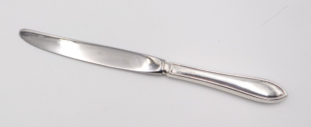 A comprehensive silver cutlery set containing dinner knives, forks, soup spoons, and dessert spoons laid out flat on a light grey background. View X