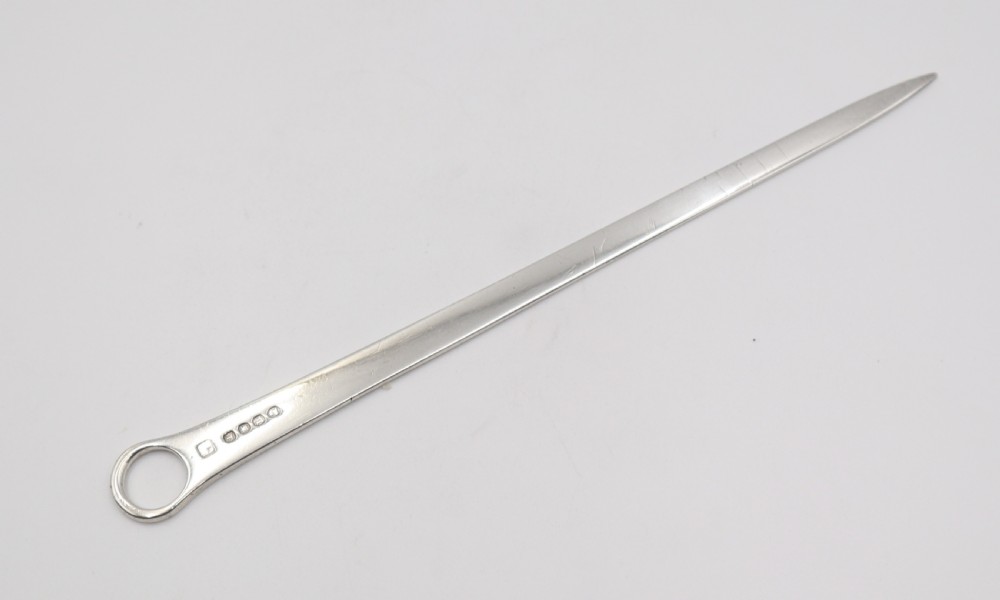 An antique sterling silver meat skewer with a tapered blade, stamped hallmarks, and a ring terminal against a neutral white backdrop.
