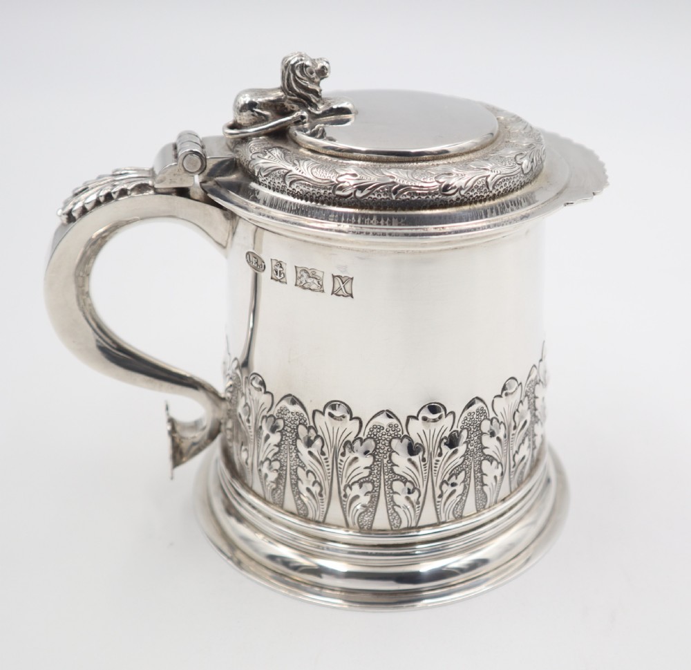 A sterling silver lidded tankard featuring chased acanthus leaf decoration, a scroll handle, visible hallmarks, and a lion thumbpiece. View VIII