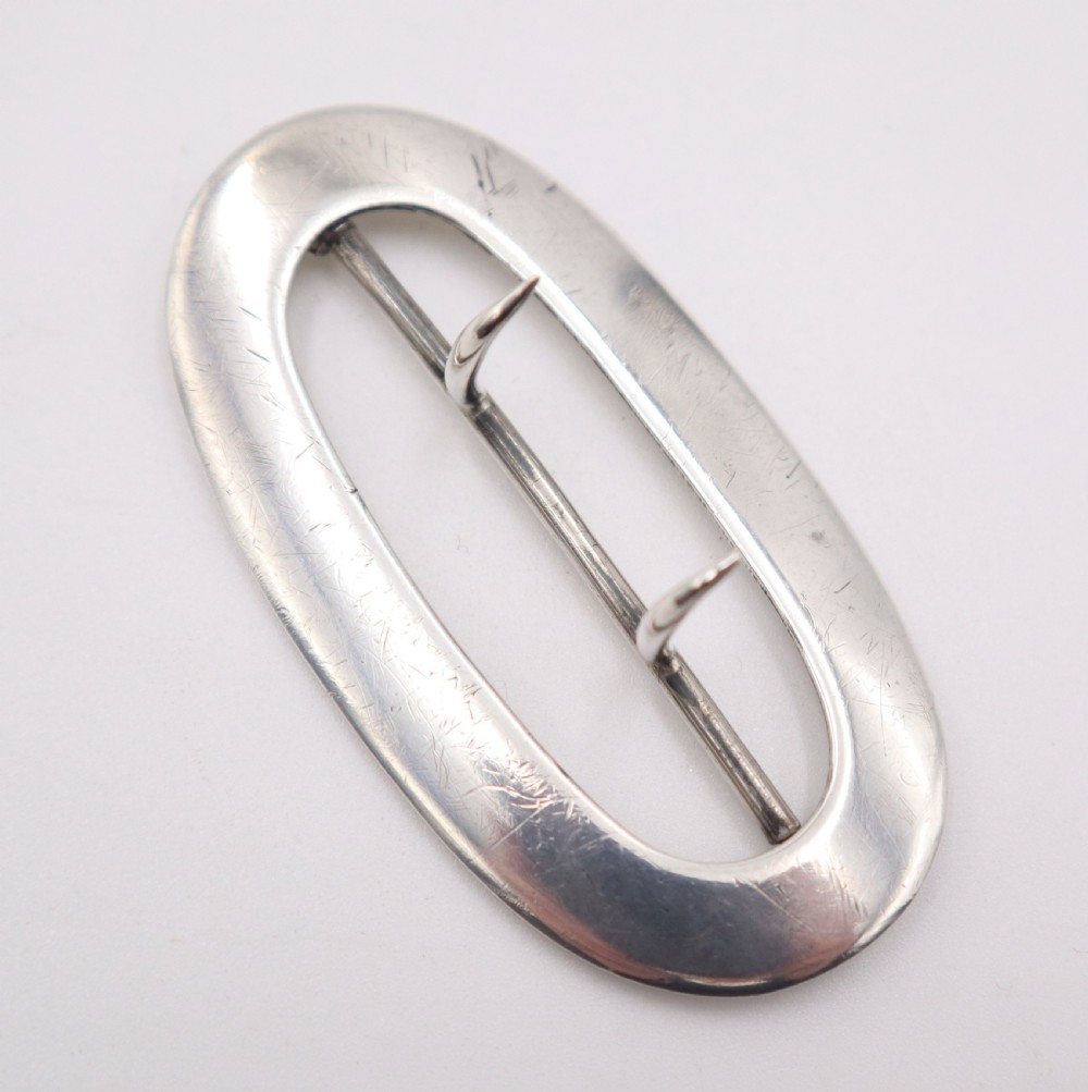 An oval sterling silver buckle featuring a central vertical bar with two pointed prongs. View II
