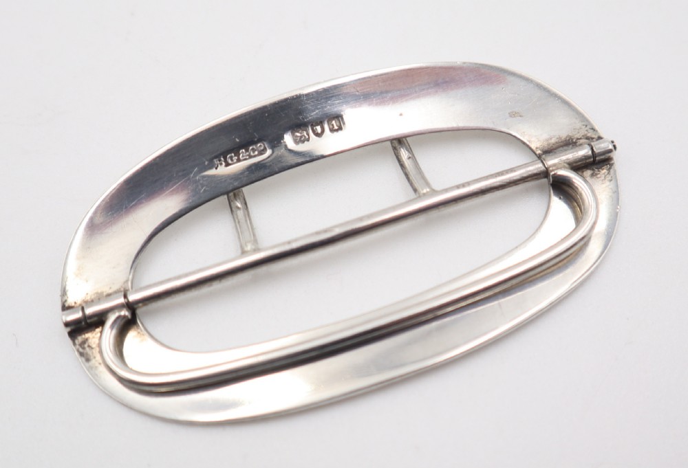 An oval sterling silver buckle featuring a central vertical bar with two pointed prongs. View IV