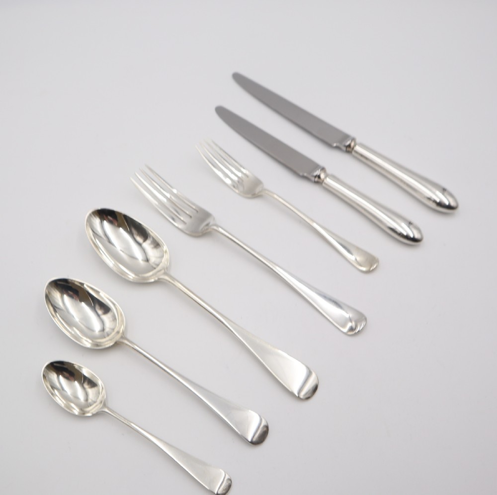 A complete antique silver cutlery set comprising table knives, forks, soup spoons, dessert spoons, and teaspoons arranged neatly on a white background. View III