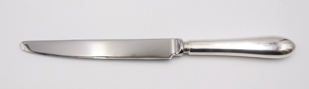 A complete antique silver cutlery set comprising table knives, forks, soup spoons, dessert spoons, and teaspoons arranged neatly on a white background. View IV