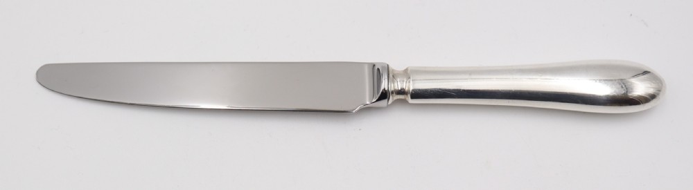 A complete antique silver cutlery set comprising table knives, forks, soup spoons, dessert spoons, and teaspoons arranged neatly on a white background. View VI