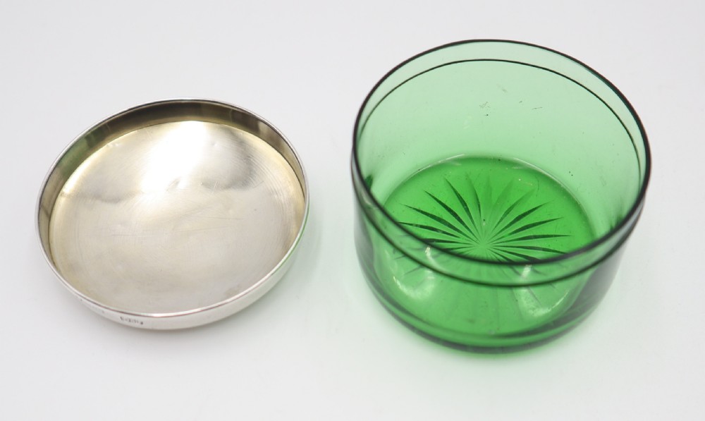 A circular green glass vanity jar featuring a cut starburst pattern on the base and a fitted polished silver lid. View III