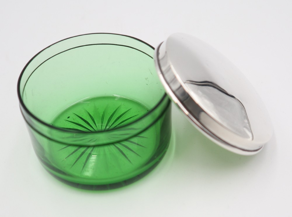 A circular green glass vanity jar featuring a cut starburst pattern on the base and a fitted polished silver lid. View IV