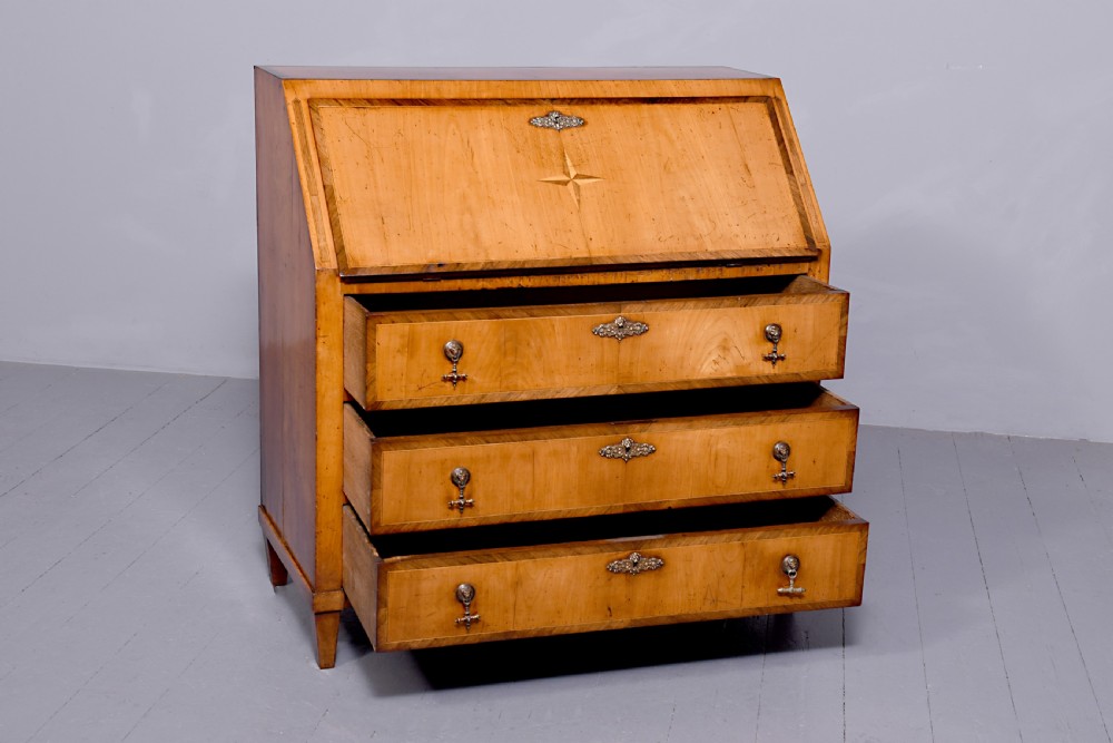 A 19th-century blonde walnut slant-front bureau featuring rosewood inlay, a central star motif on the lid, and three long drawers with decorative metal handles. View II