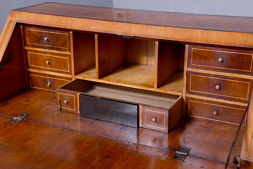 A 19th-century blonde walnut slant-front bureau featuring rosewood inlay, a central star motif on the lid, and three long drawers with decorative metal handles. View IV