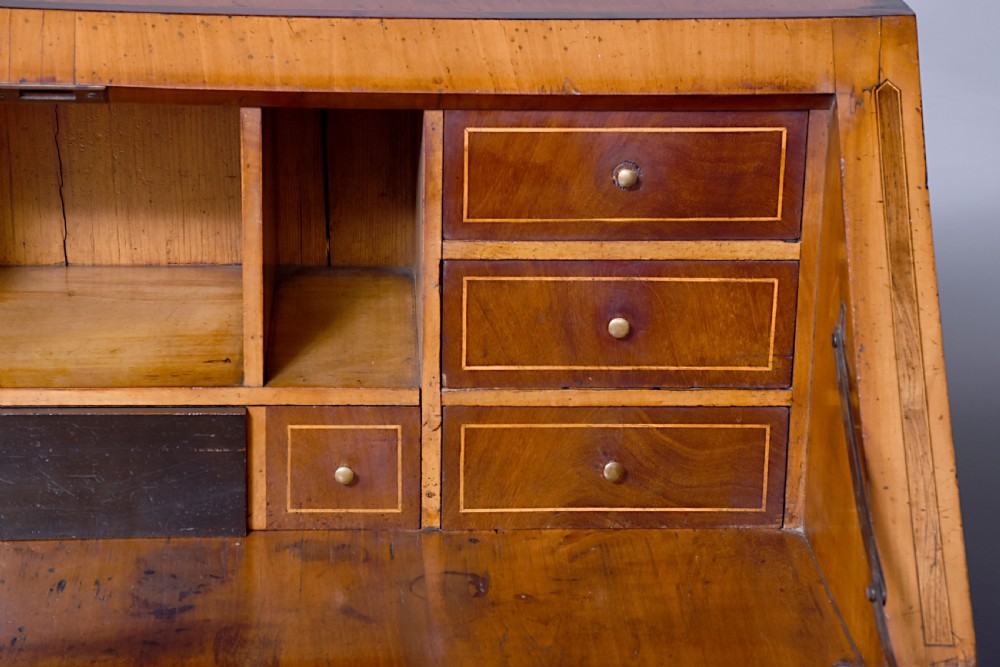A 19th-century blonde walnut slant-front bureau featuring rosewood inlay, a central star motif on the lid, and three long drawers with decorative metal handles. View V