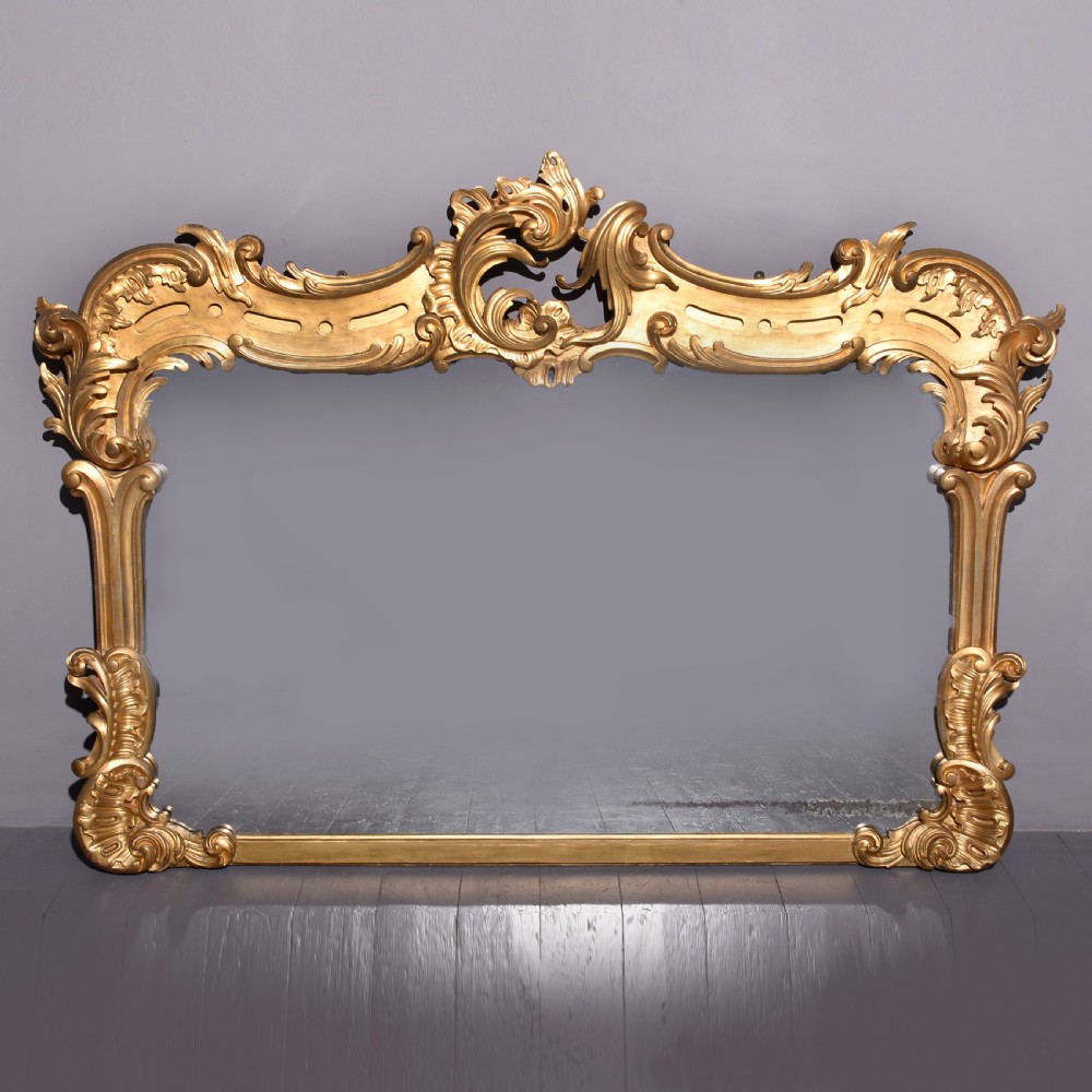 A William IV gilded overmantel mirror with Rococo scrollwork and carved acanthus leaf cresting.