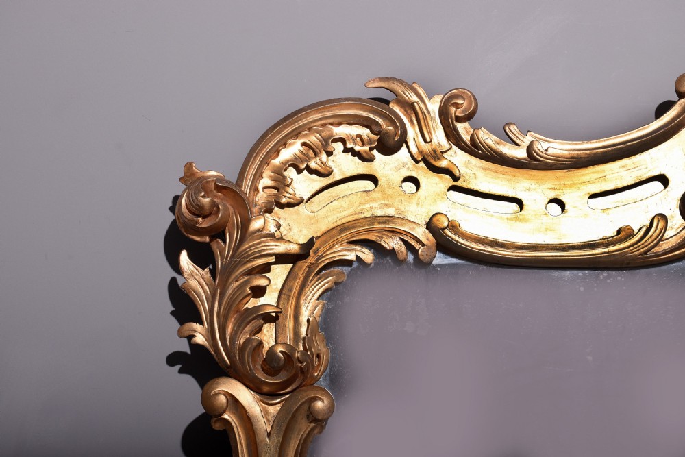 A William IV gilded overmantel mirror with Rococo scrollwork and carved acanthus leaf cresting. View III