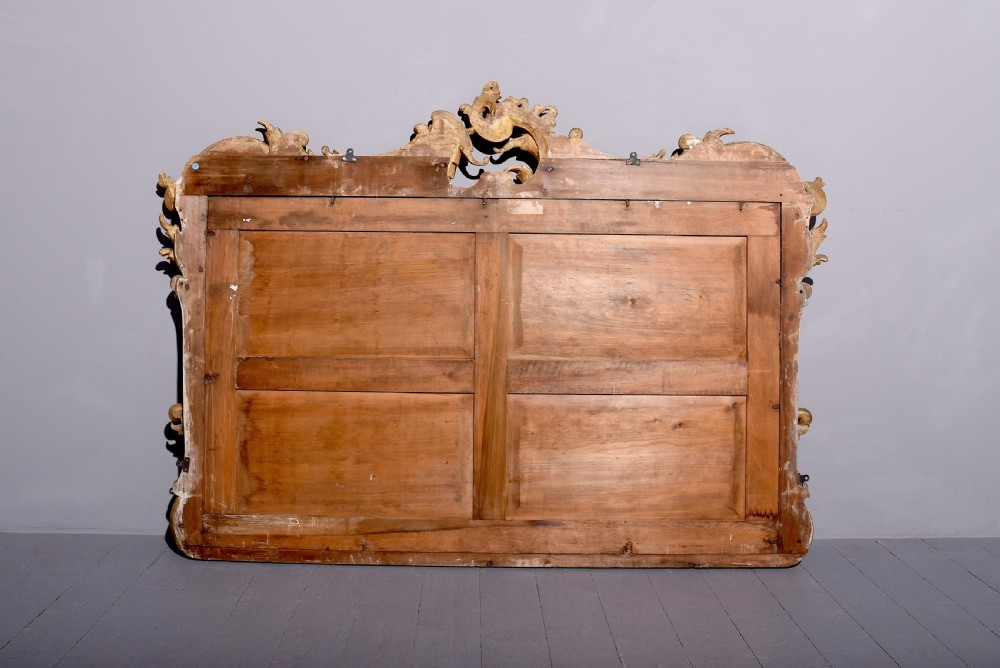 A William IV gilded overmantel mirror with Rococo scrollwork and carved acanthus leaf cresting. View V