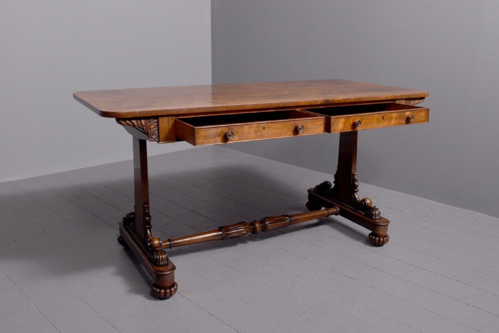 A William IV rosewood library table featuring a rectangular top, two frieze drawers, carved scroll brackets, end pedestal supports, and a turned central stretcher. View VI