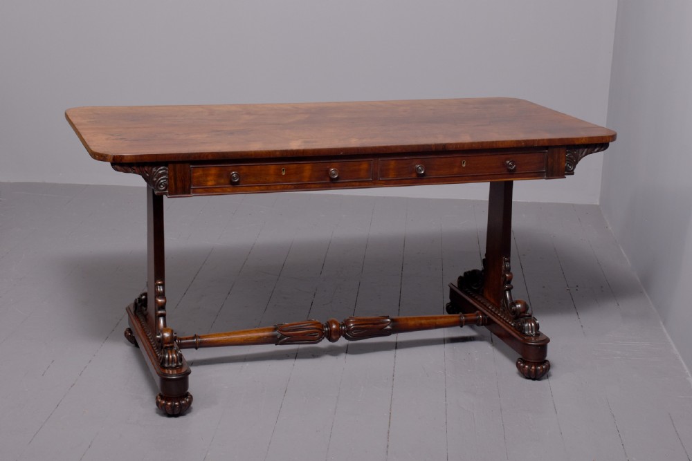 A William IV rosewood library table featuring a rectangular top, two frieze drawers, carved scroll brackets, end pedestal supports, and a turned central stretcher. View IX