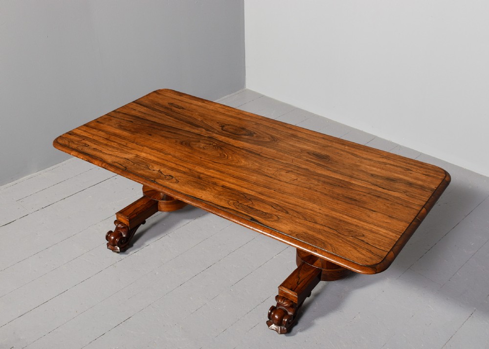 A low rectangular rosewood coffee table featuring twin turned pedestal supports, carved scroll feet, and brass castors. View II