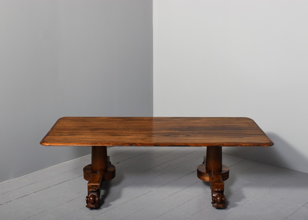 A low rectangular rosewood coffee table featuring twin turned pedestal supports, carved scroll feet, and brass castors. View VII