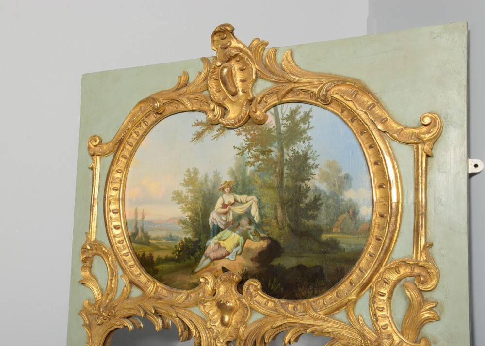 A large French trumeau wall mirror featuring a pale sage green painted panel base, elaborate gold gilt scrollwork framing, an upper oval pastoral oil painting, and a lower rectangular mirror glass. View III