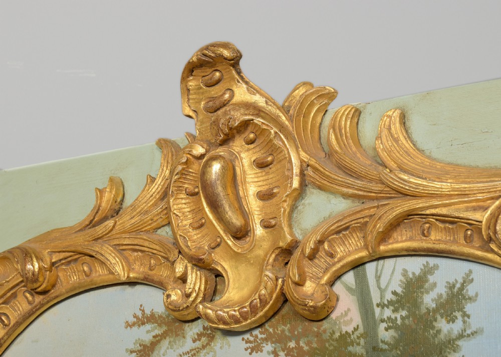 A large French trumeau wall mirror featuring a pale sage green painted panel base, elaborate gold gilt scrollwork framing, an upper oval pastoral oil painting, and a lower rectangular mirror glass. View IV