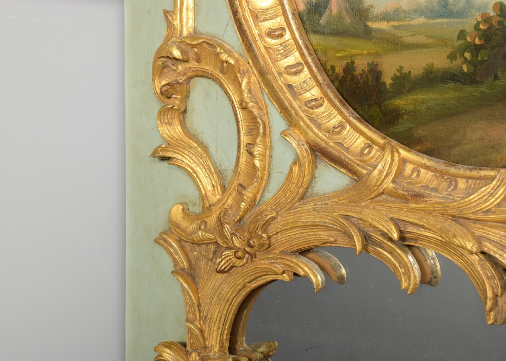 A large French trumeau wall mirror featuring a pale sage green painted panel base, elaborate gold gilt scrollwork framing, an upper oval pastoral oil painting, and a lower rectangular mirror glass. View VI