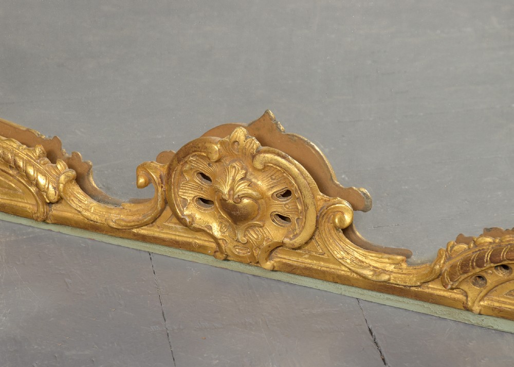 A large French trumeau wall mirror featuring a pale sage green painted panel base, elaborate gold gilt scrollwork framing, an upper oval pastoral oil painting, and a lower rectangular mirror glass. View VII
