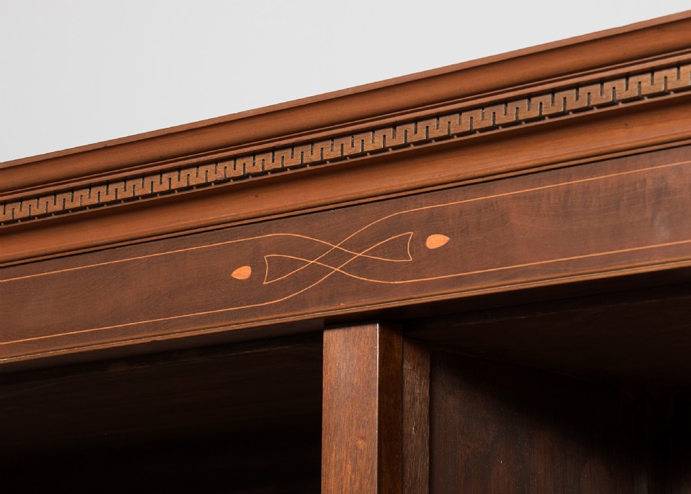 A wide dark mahogany open bookcase featuring twin double bays with multiple shelves, decorative inlay on the frieze, carved shell motifs on the lower apron, and cabriole legs ending in ball and claw feet. View V