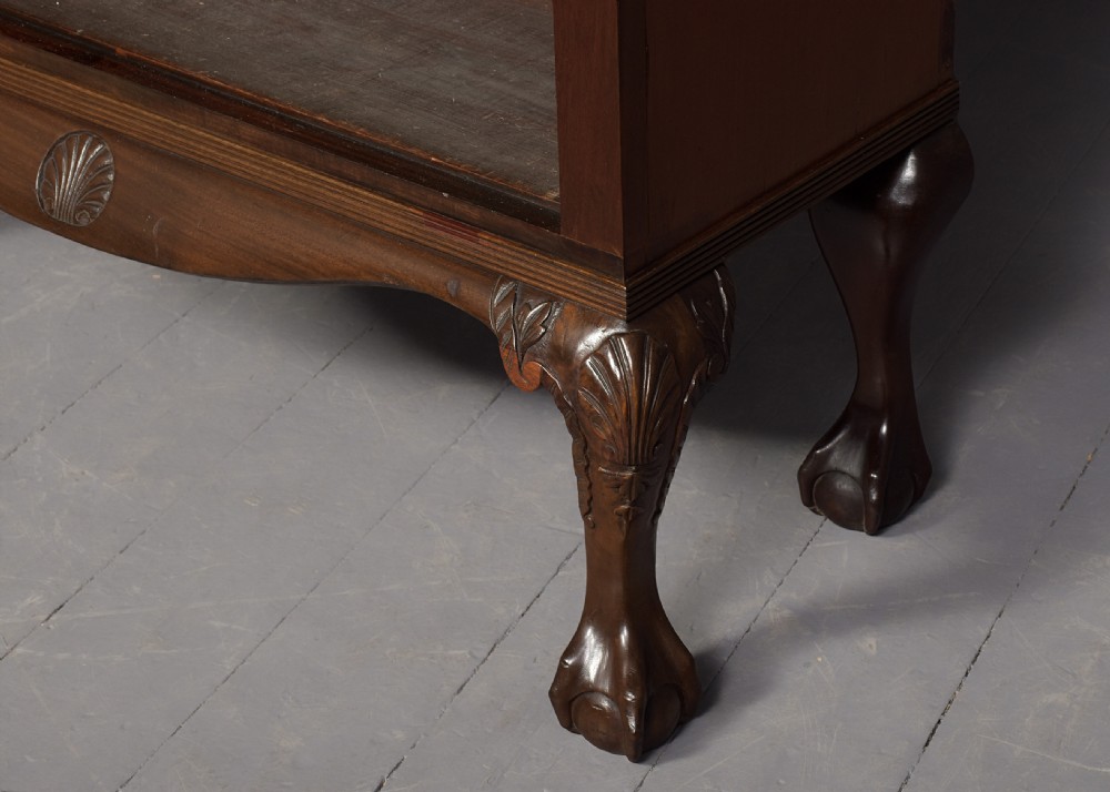A wide dark mahogany open bookcase featuring twin double bays with multiple shelves, decorative inlay on the frieze, carved shell motifs on the lower apron, and cabriole legs ending in ball and claw feet. View VII