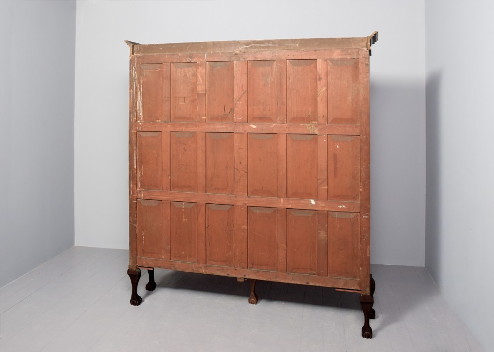 A wide dark mahogany open bookcase featuring twin double bays with multiple shelves, decorative inlay on the frieze, carved shell motifs on the lower apron, and cabriole legs ending in ball and claw feet. View X
