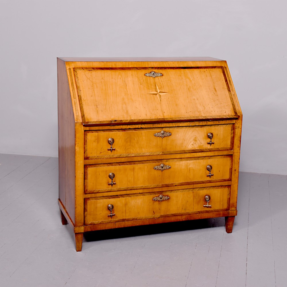A 19th-century blonde walnut slant-front bureau featuring rosewood inlay, a central star motif on the lid, and three long drawers with decorative metal handles.