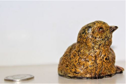 fig 1. A small cold-painted bronze figurine depicting a young chick with textured yellow and brown feathers.
