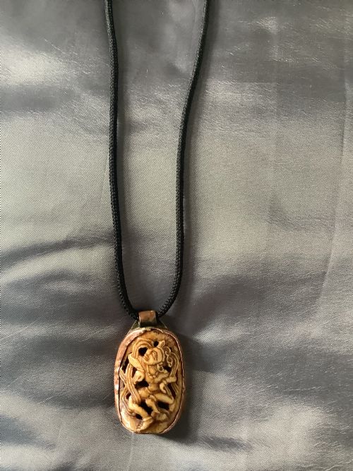A VERY FINELY CARVED BONE INDIAN PENDANT ENCASED IN A METAL FRAME - ADDITIONAL PHOTO 3