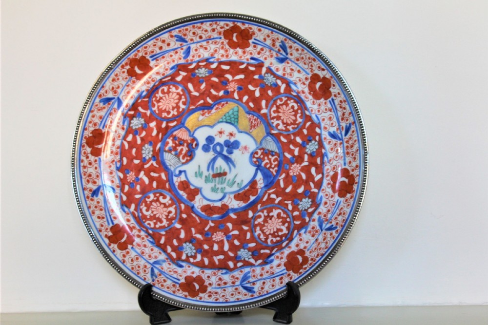 A circular Chinese Imari porcelain charger featuring hand-painted iron-red and underglaze blue floral patterns with a beaded metal outer rim. View II