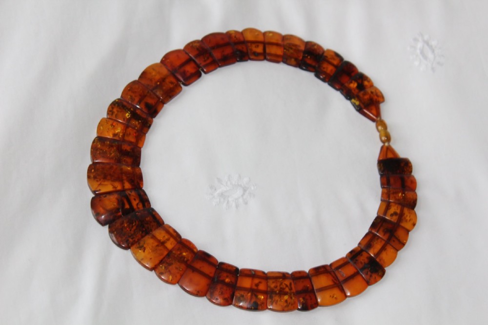 An Art Deco Baltic amber necklace featuring graduated rectangular polished cognac amber beads strung in a curved collar layout.