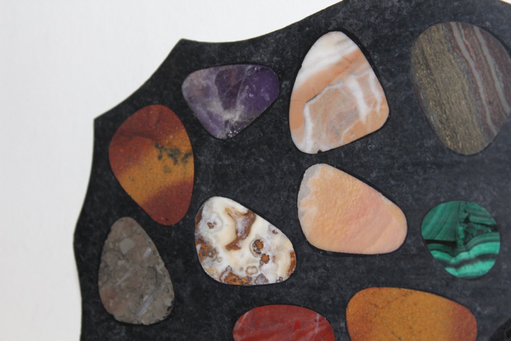 A shaped dark slate plaque inlaid with various polished colorful specimen stones including malachite and agates. View V