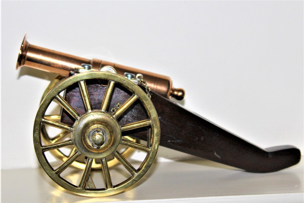 A pair of antique polished bronze desk cannons mounted on dark mahogany wooden carriages with brass spoked wheels. View III
