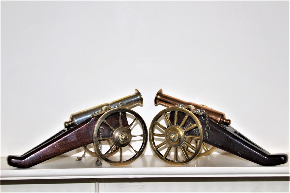 A pair of antique polished bronze desk cannons mounted on dark mahogany wooden carriages with brass spoked wheels. View VI