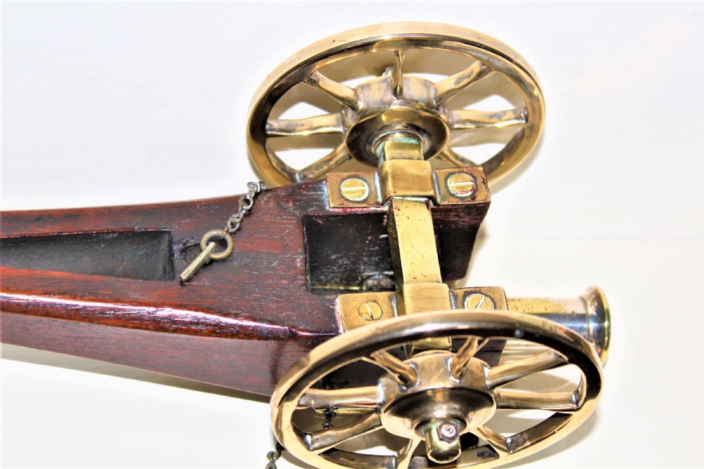 A pair of antique polished bronze desk cannons mounted on dark mahogany wooden carriages with brass spoked wheels. View VII