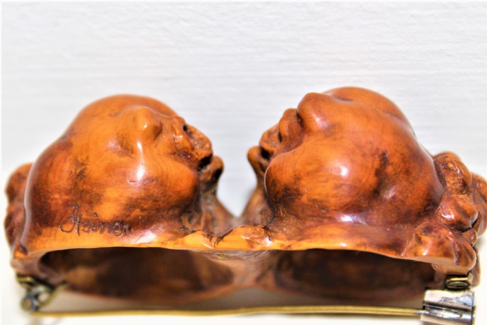 A carved boxwood brooch depicting two cherub heads in profile facing each other with detailed curly hair. View IV