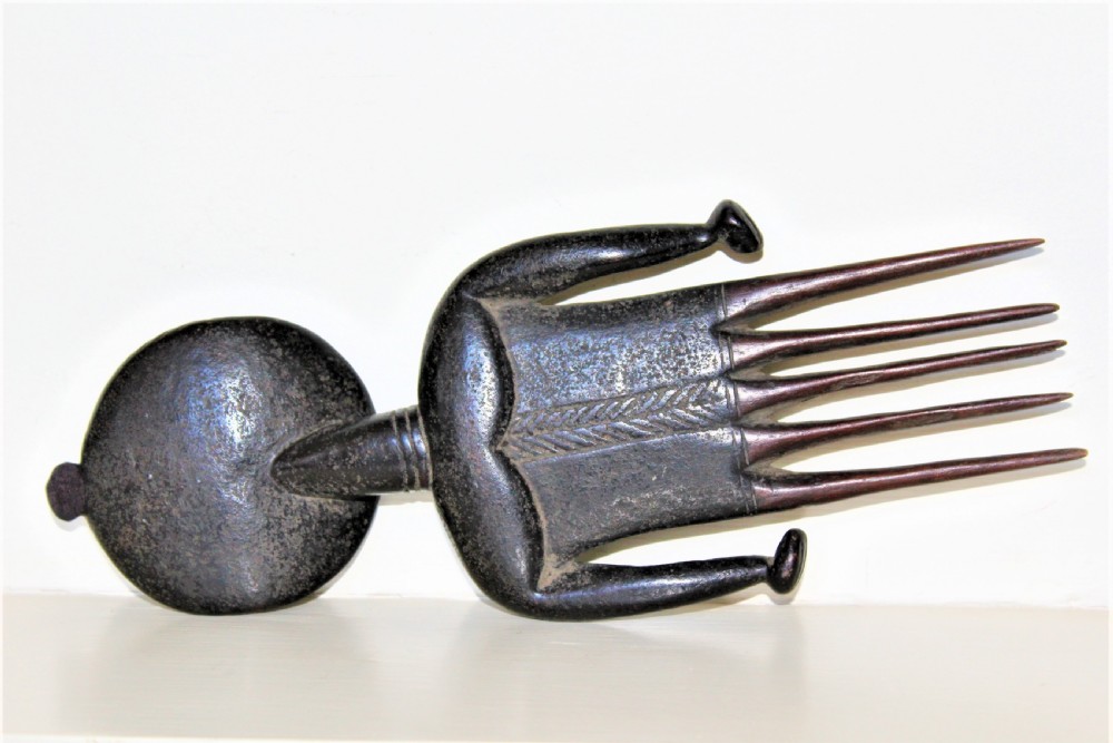 A carved dark hardwood West African comb featuring a stylized female form above five long tines. View IV