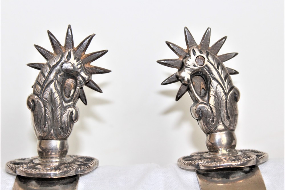 A pair of ornate late 19th-century South American metal spurs featuring multi-pointed starburst rowels and dangling charms. View II