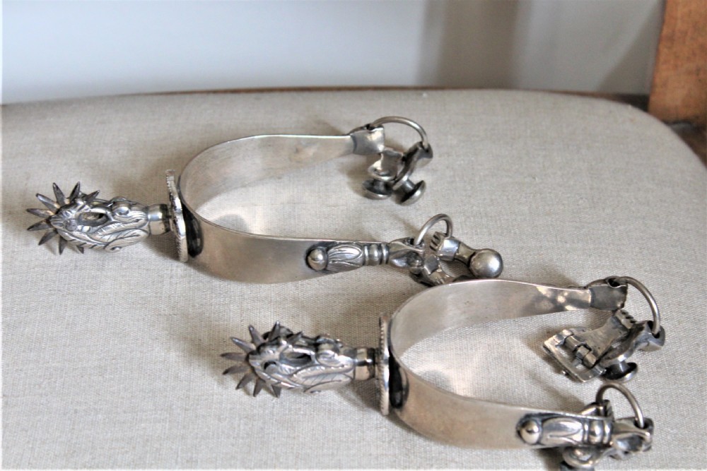 A pair of ornate late 19th-century South American metal spurs featuring multi-pointed starburst rowels and dangling charms. View VI