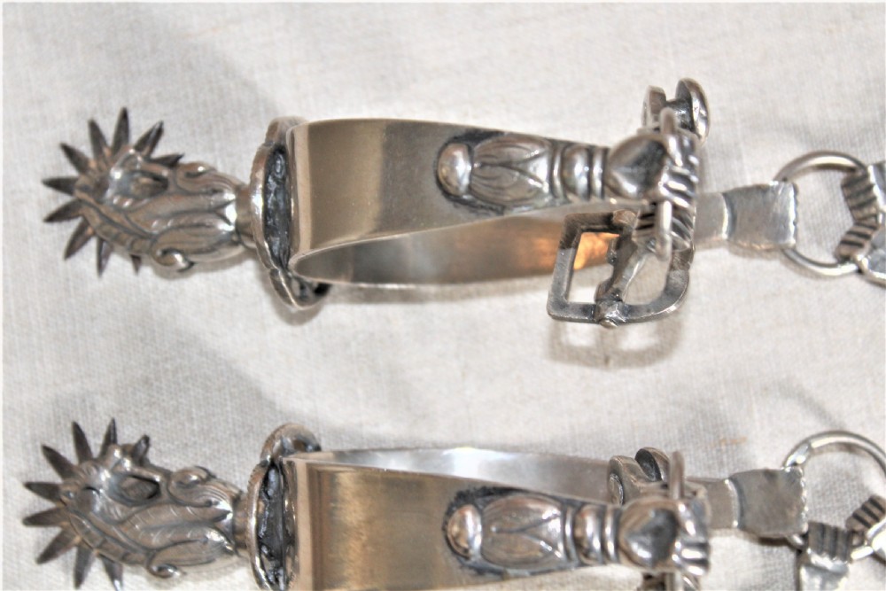 A pair of ornate late 19th-century South American metal spurs featuring multi-pointed starburst rowels and dangling charms. View VII
