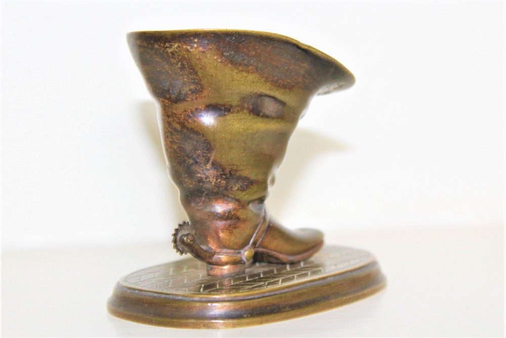 A 19th-century cast bronze paperweight shaped like a folded riding boot with a rowel spur on an oval engraved base. View III