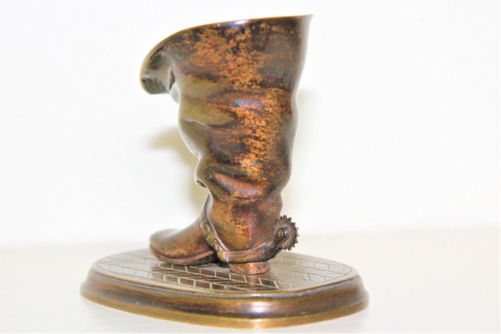 A 19th-century cast bronze paperweight shaped like a folded riding boot with a rowel spur on an oval engraved base. View IV