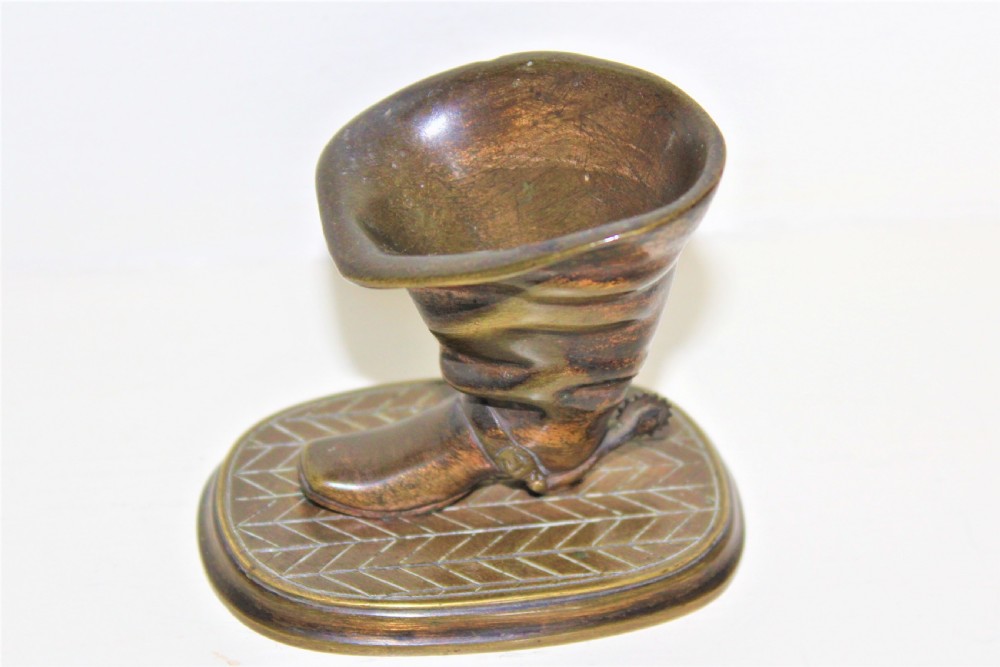A 19th-century cast bronze paperweight shaped like a folded riding boot with a rowel spur on an oval engraved base. View V