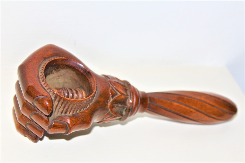 A late 19th-century carved brown wood nutcracker in the form of a clenched hand holding a nut. View II