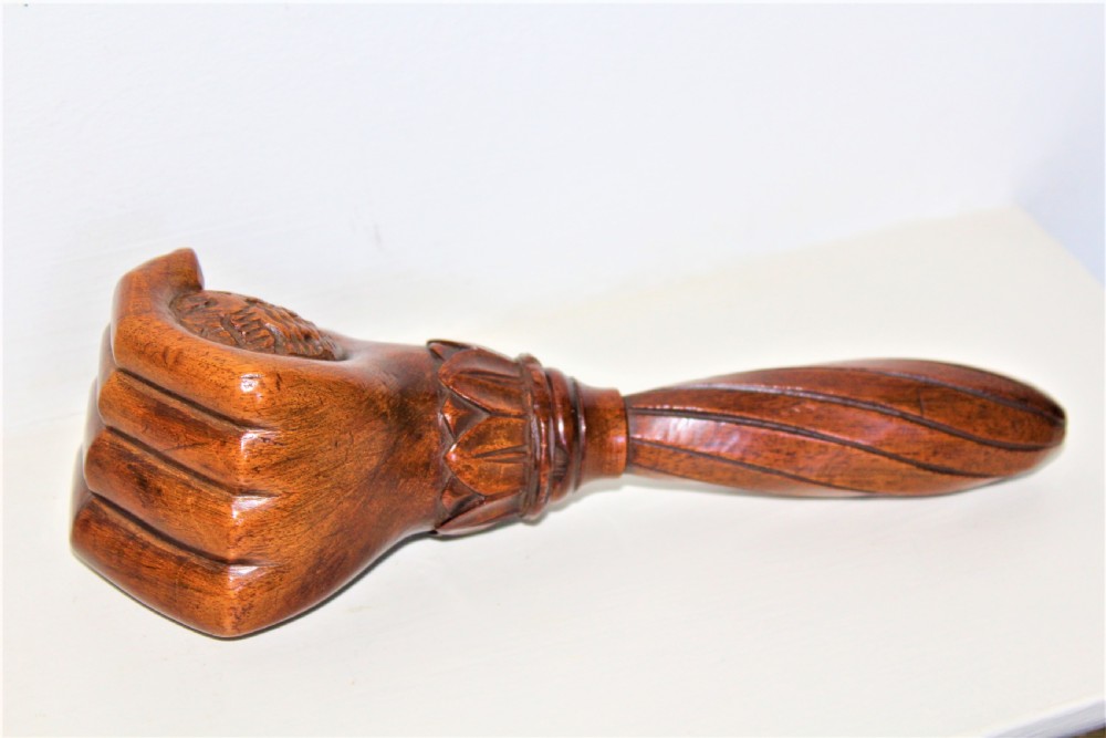A late 19th-century carved brown wood nutcracker in the form of a clenched hand holding a nut. View III