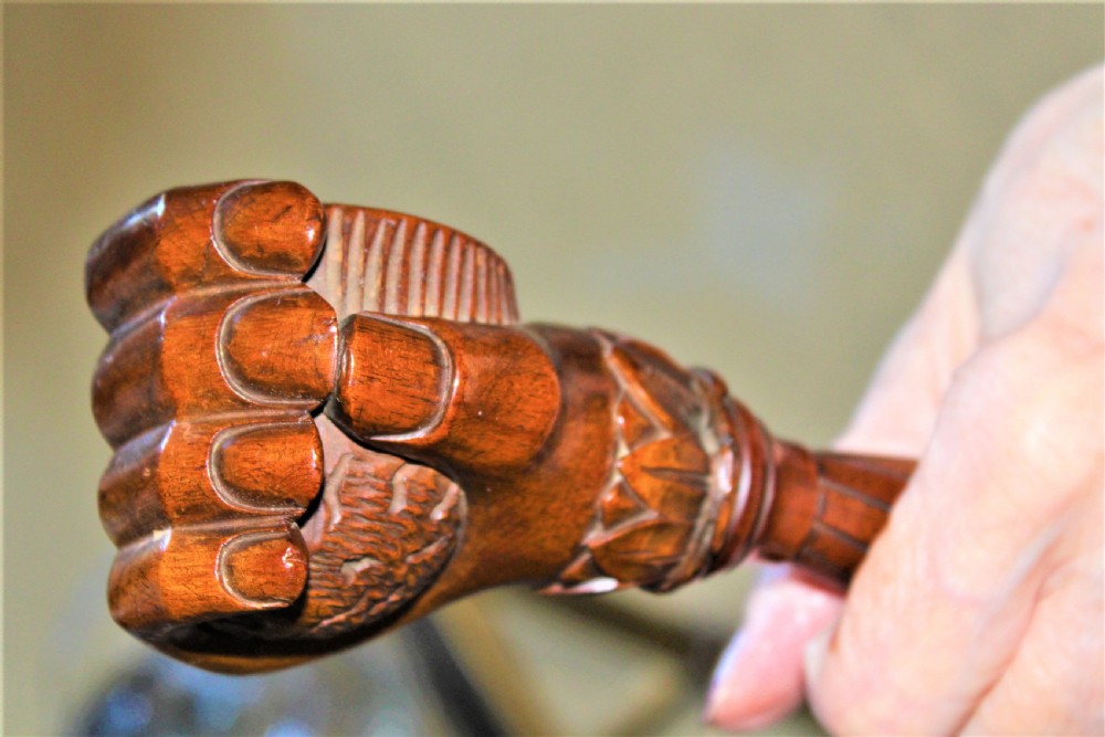 A late 19th-century carved brown wood nutcracker in the form of a clenched hand holding a nut. View VI