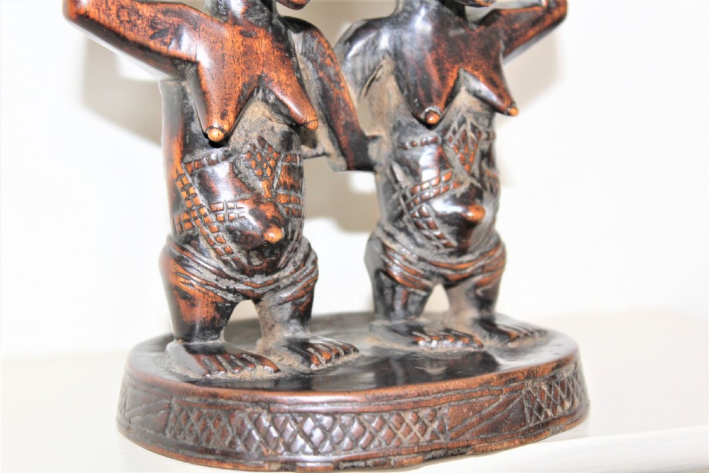 A carved dark hardwood headrest supported by two standing female caryatid figures on a circular carved base. View VI